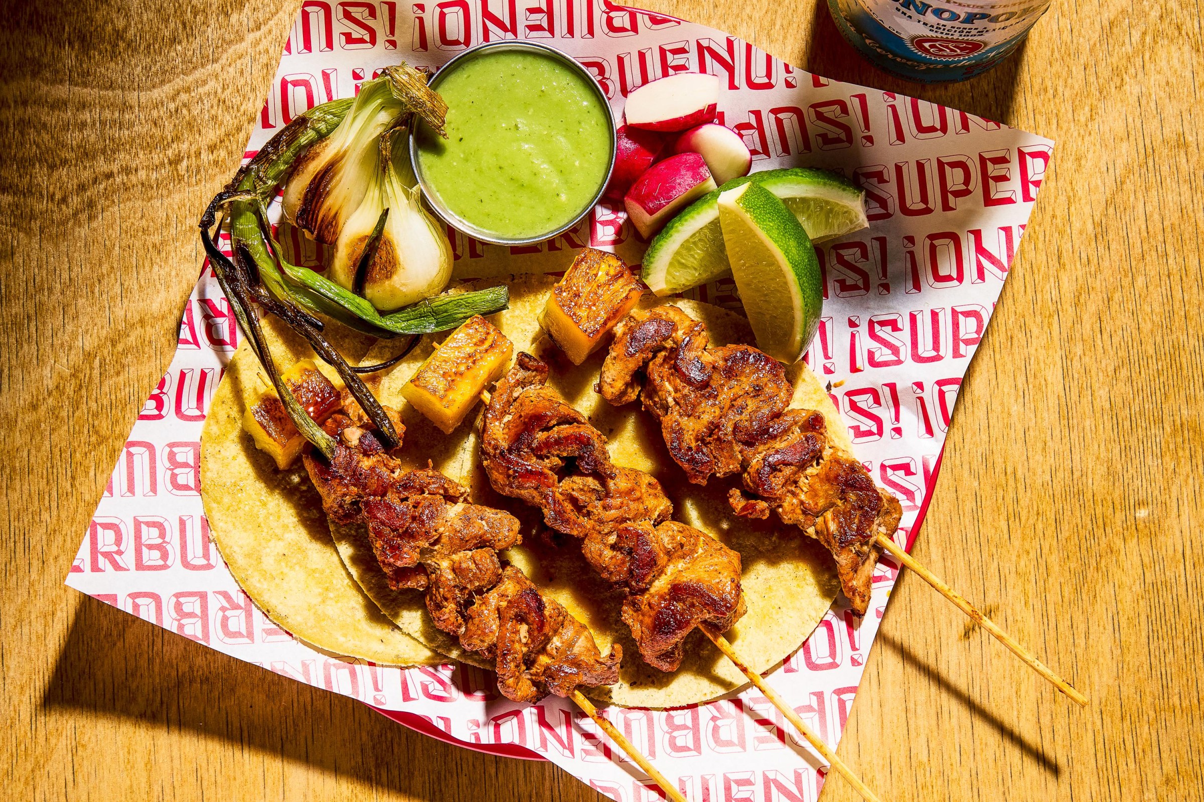 A plate of meat on skewers on top of a tortilla.