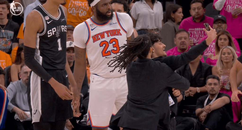 Victor Wembanyama and Mitchell Robinson watch as a fan runs onto the court.
