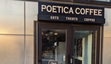 Entrance to a Poetica Coffee location in New York City, featuring the café's black storefront sign above glass doors and windows.