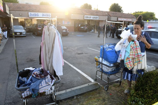 A woman gathers her laundry after she saw another woman get killed when a car crashed into the Suds & Duds laundromat in Manhattan Beach on Tuesday June 9. (Photo by Axel Koester, Contributing Photographer)