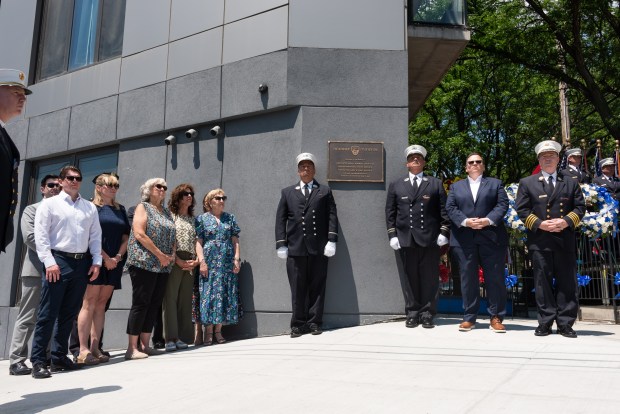 Family members, left, look on as a plaque is unveiled at the site of the 2001 Father's Day fire on Astoria Blvd. and 14th St. in Queens, New York, during a ceremony on Wednesday, June 17, 2026. (Gardiner Anderson / New York Daily News)
