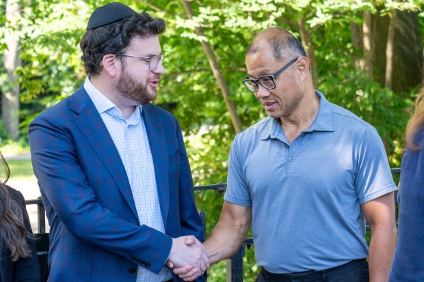 State Senator John Liu, right, greets Albert Iskowitz's son Tzvi Yonie Itzkowitz at a press conference in Kissena Park on Thursday.
