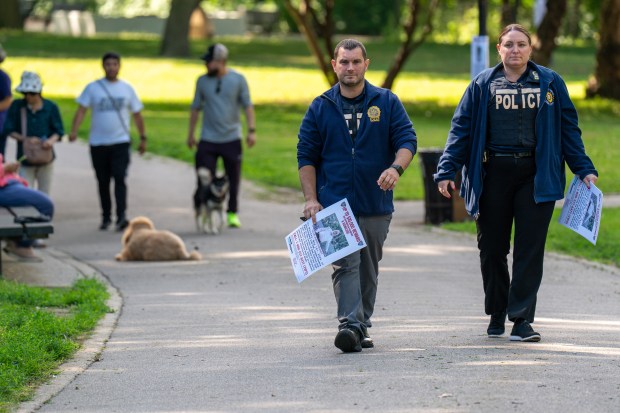 Police in Kissena Park on Thursday carry posters seeking information on the death of Albert Itzkowitz.