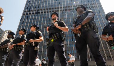 A photo shows a group of New York police officers in uniform stand in a line outdoors.