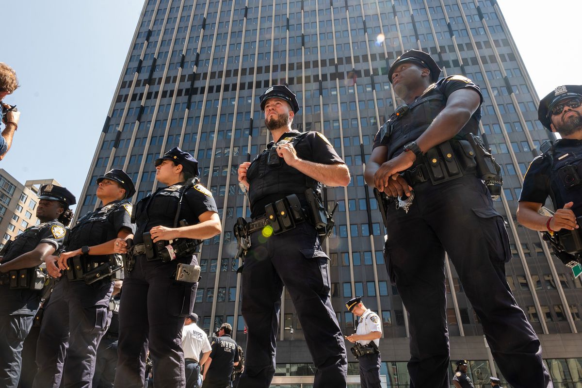 A photo shows a group of New York police officers in uniform stand in a line outdoors.
