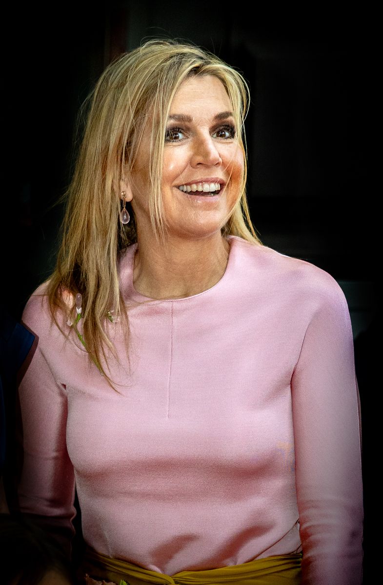 A closer look at Queen Máxima's glamorous beauty look, featuring softly tousled blonde hair, luminous makeup, and delicate pink gemstone drop earrings.