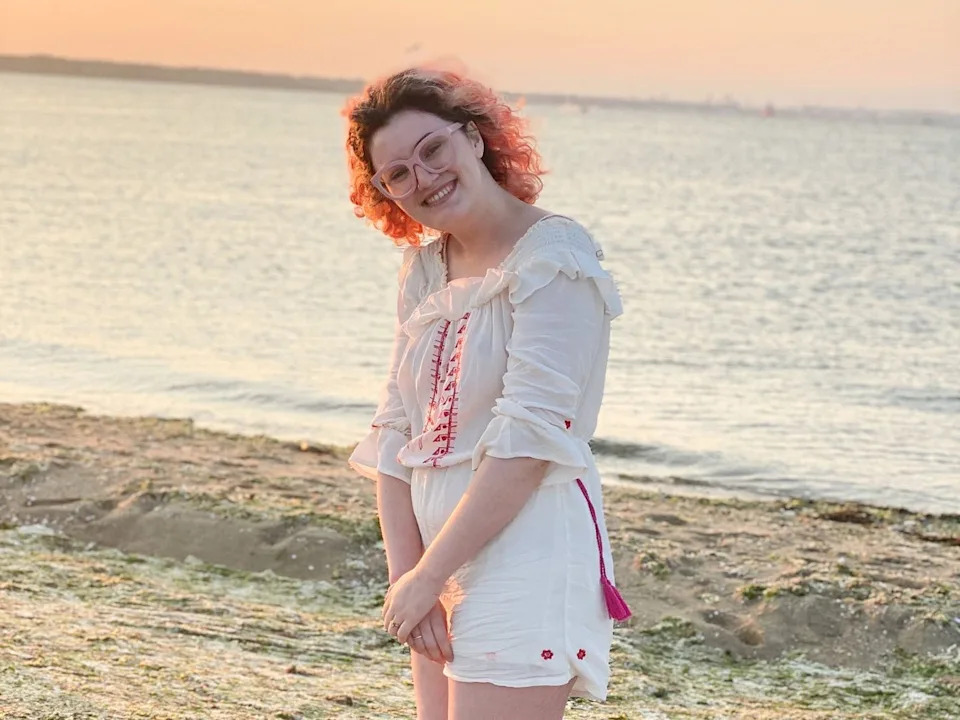 Rachel stands on a beach at dusk.