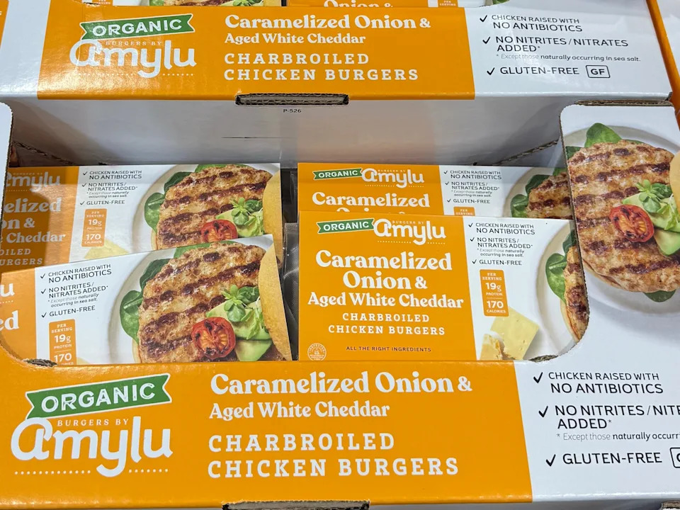 Multiple boxes of Amylu organic chicken burgers with caramelized onion and aged white cheddar.