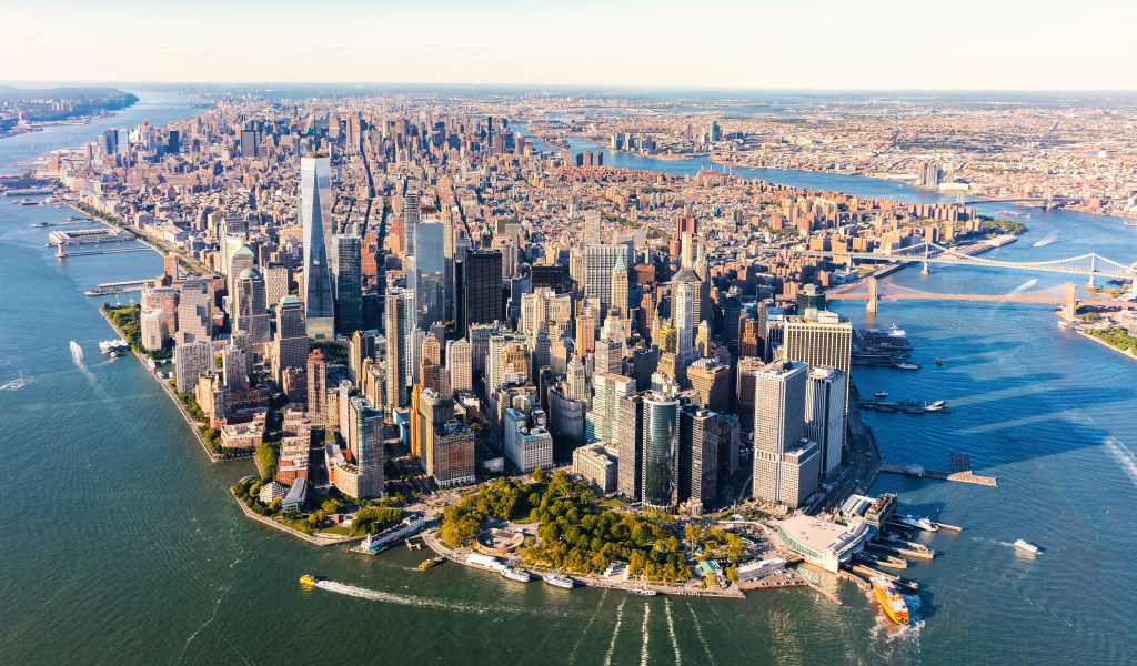 Aerial view of Lower Manhattan, New York City, showing its financial district skyscrapers, the Hudson and East Rivers, and surrounding boroughs.