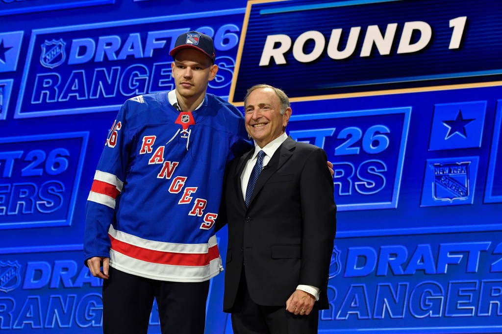 Alberts Smits, left, wearing a blue New York Rangers jersey, stands with NHL Commissioner Gary Bettman, right, at the NHL draft.