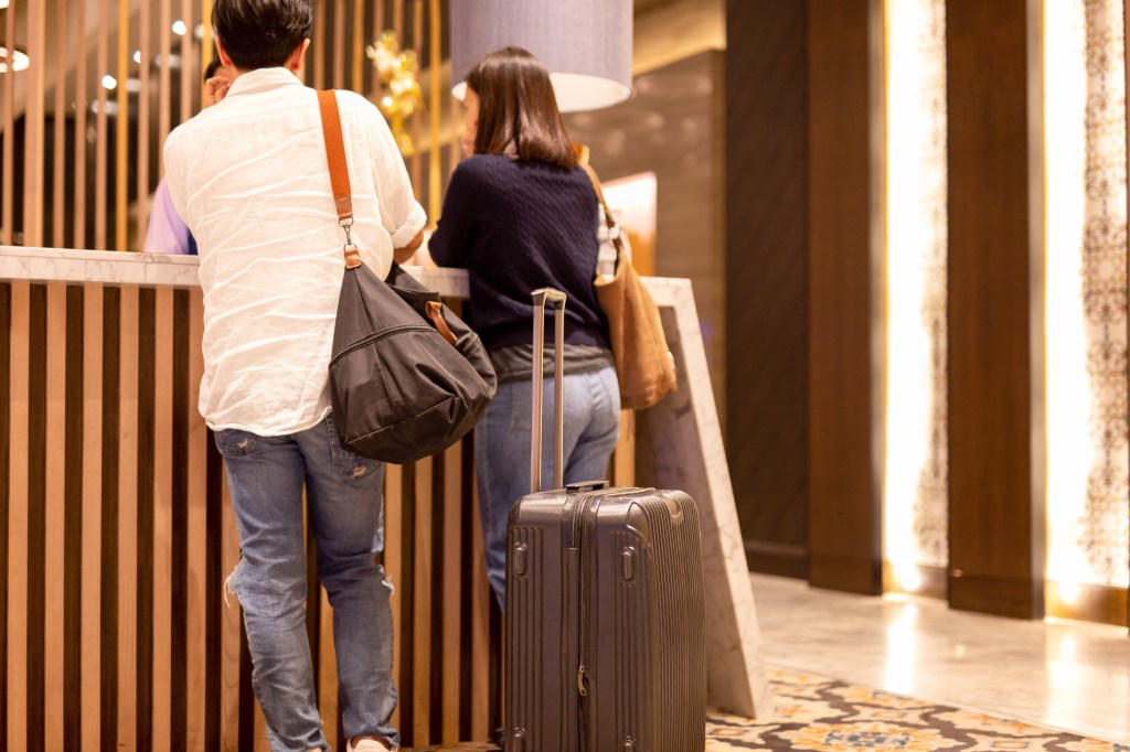 Couple checking in at a hotel reception desk with their luggage.