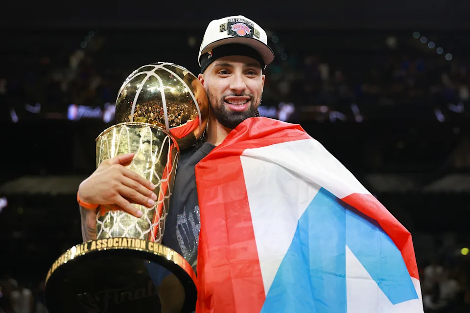 Jose Alvarado holds the Larry O'Brien trophy while draped in the Puerto Rican flag after the Knicks won the NBA championship Saturday night.