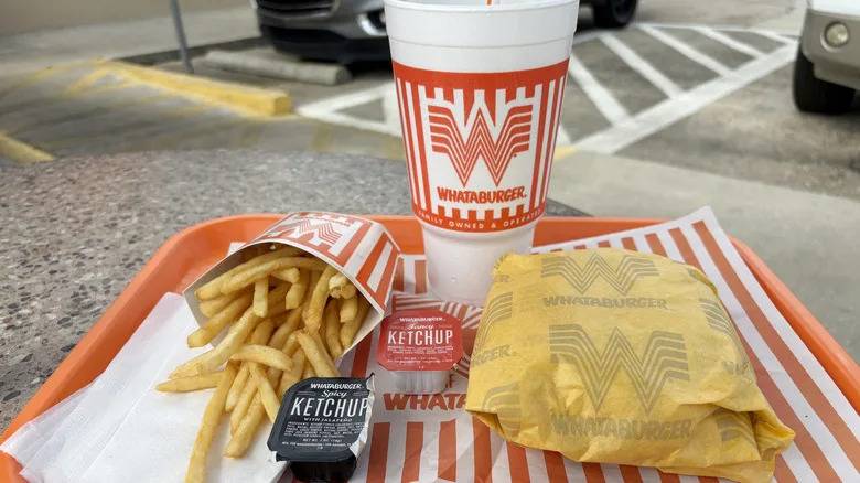A tray featuring a Whataburger cheeseburger meal with french fries and a Coca-Cola at the fast food restaurant chain.