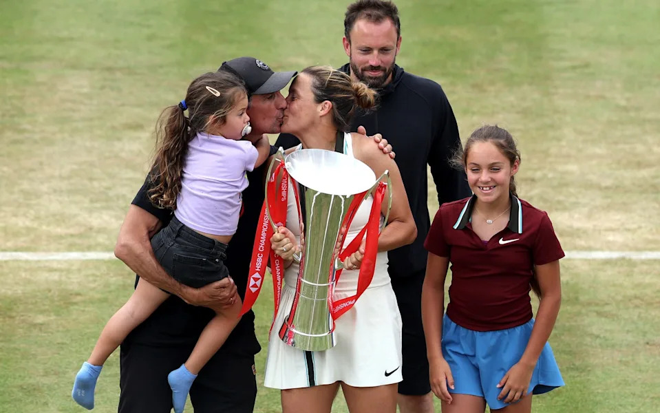 Tatjana Maria shares a kiss with her husband Charles-Edouard as she celebrates with the HSBC Championships winners trophy