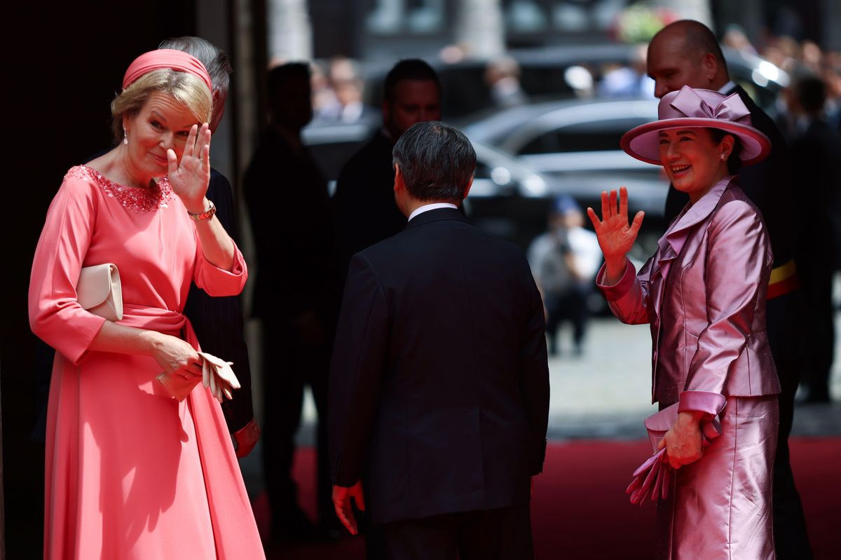 Queen Mathilde embraced daytime elegance in a coral-pink dress and coordinating fascinator as she welcomed Japan's imperial couple.