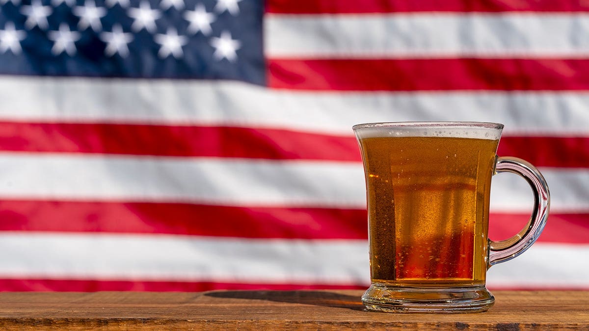 Glass of beer on wooden table with American flag in background