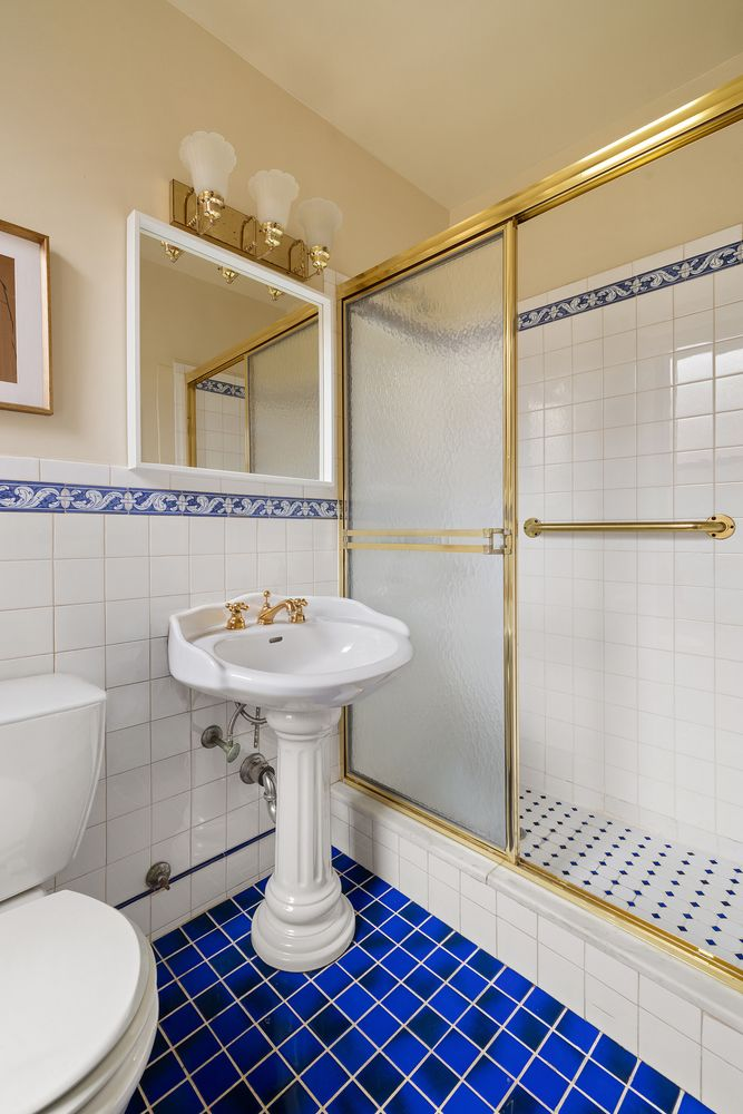 bathroom with bright blue floor tile and a shower