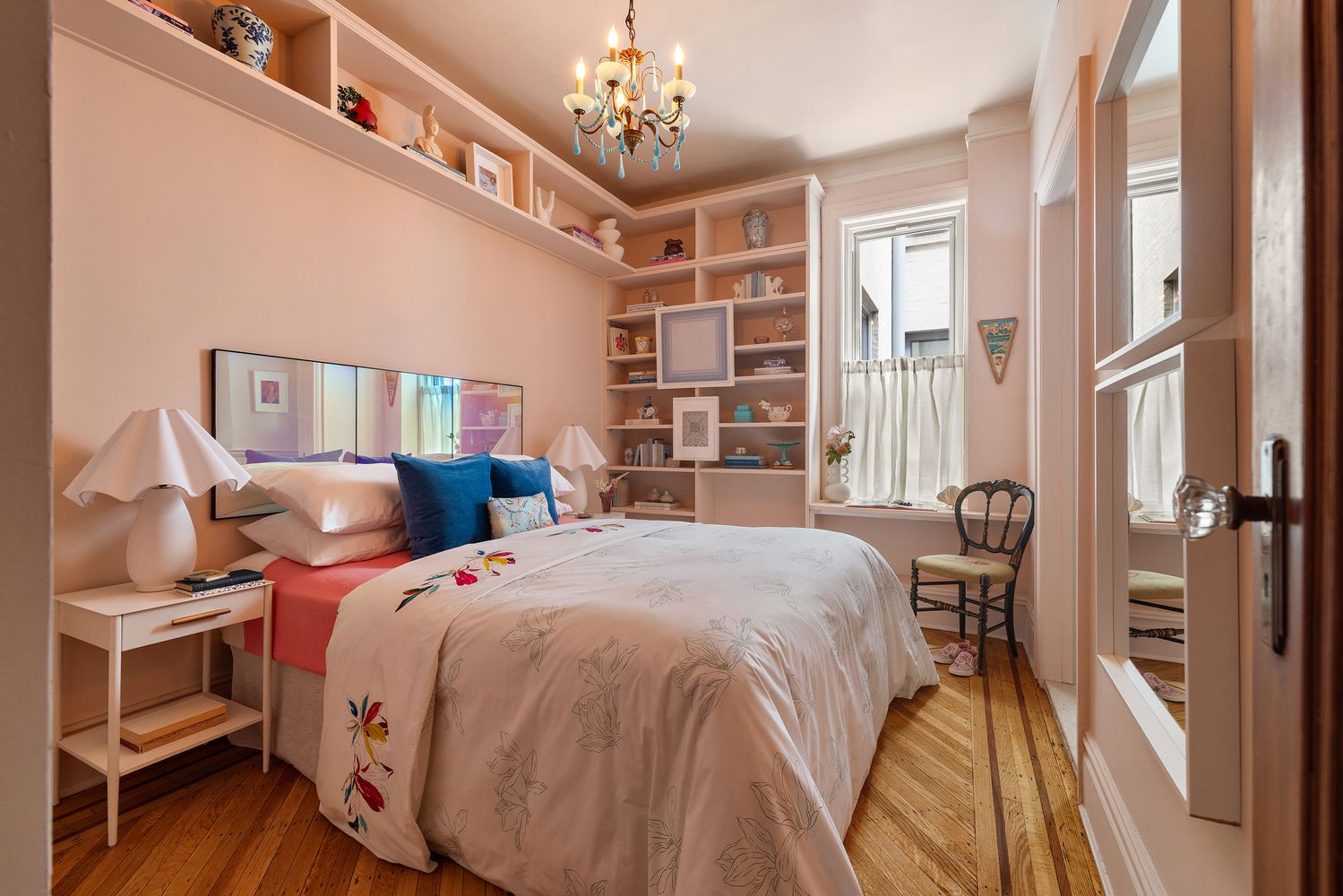 bedroom with built-in shelves, pink walls, wood floor