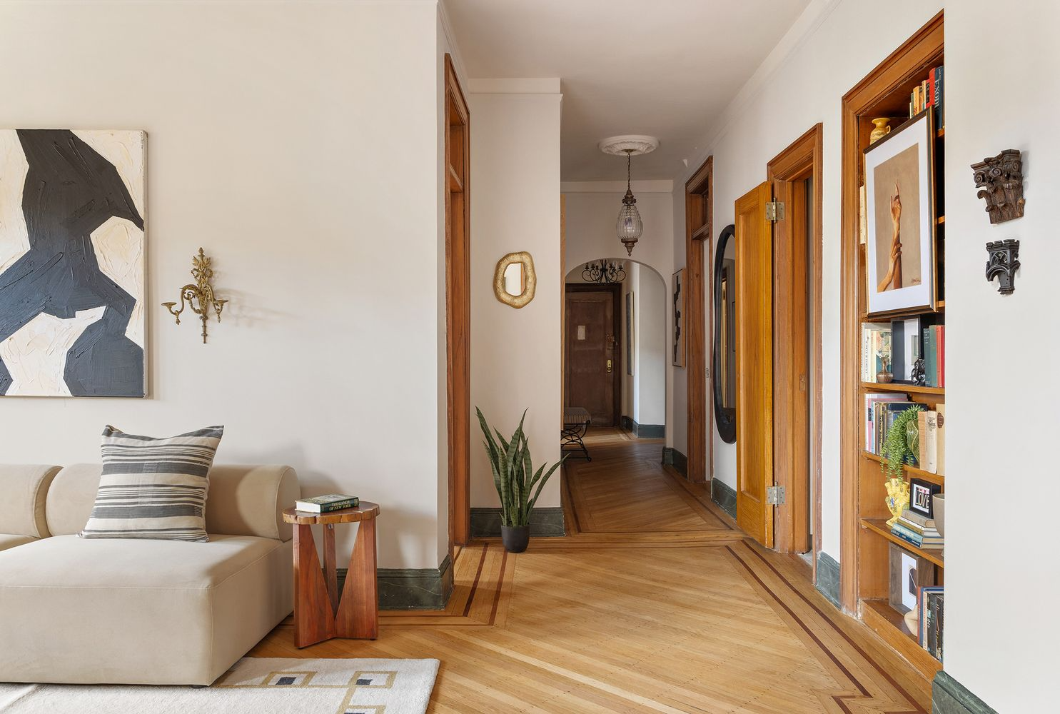 a hall with wood floor and wood moldings around built-in shelves and doorways