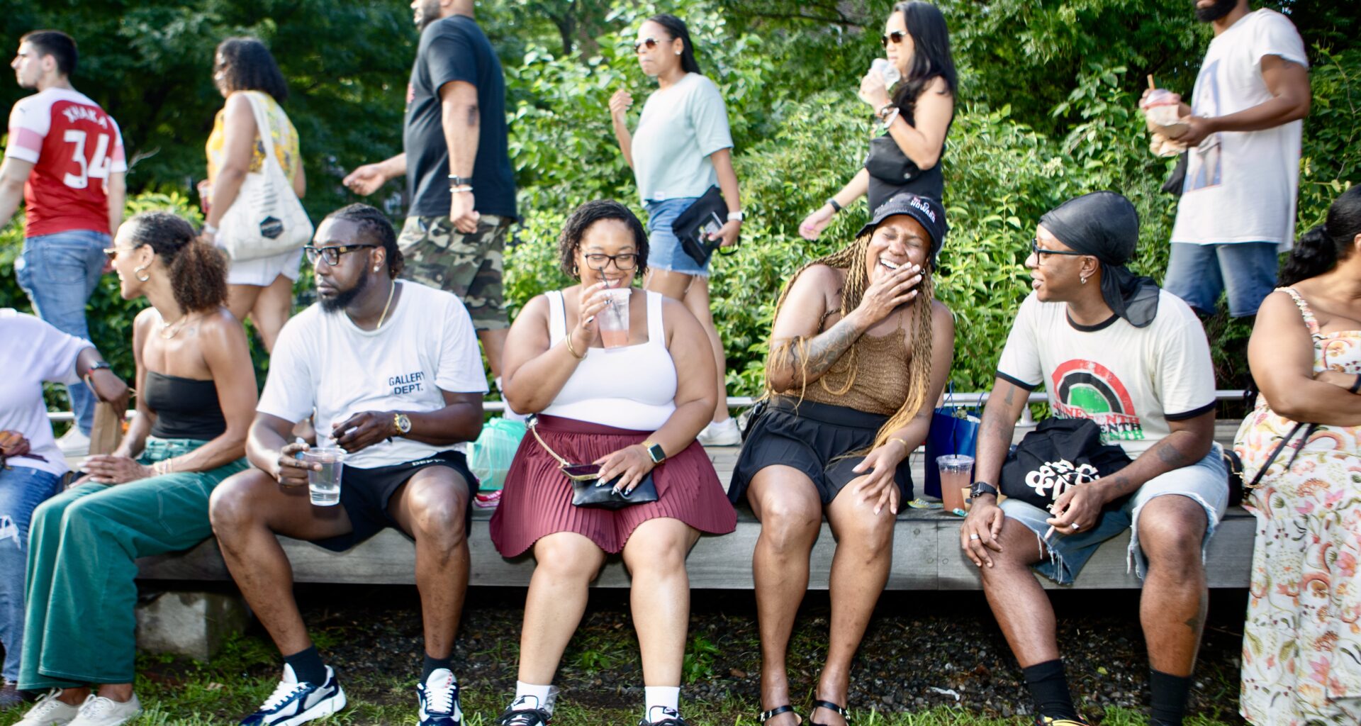 people sitting on a bench eating, drinking and laughing