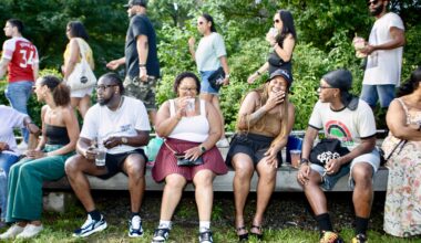 people sitting on a bench eating, drinking and laughing