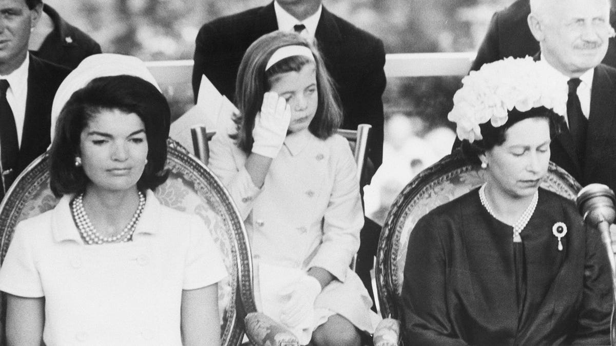 Caroline Kennedy wiping a tear from her eye at a memorial ceremony.