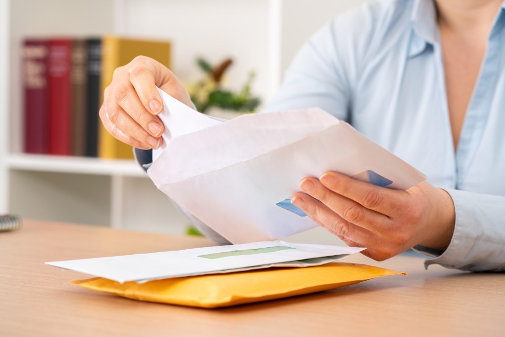 A person putting a letter inside an envelope.