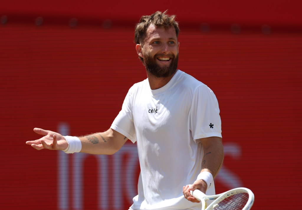 Tennis player Corentin Moutet in a white shirt and wristband, smiling and holding a racket.