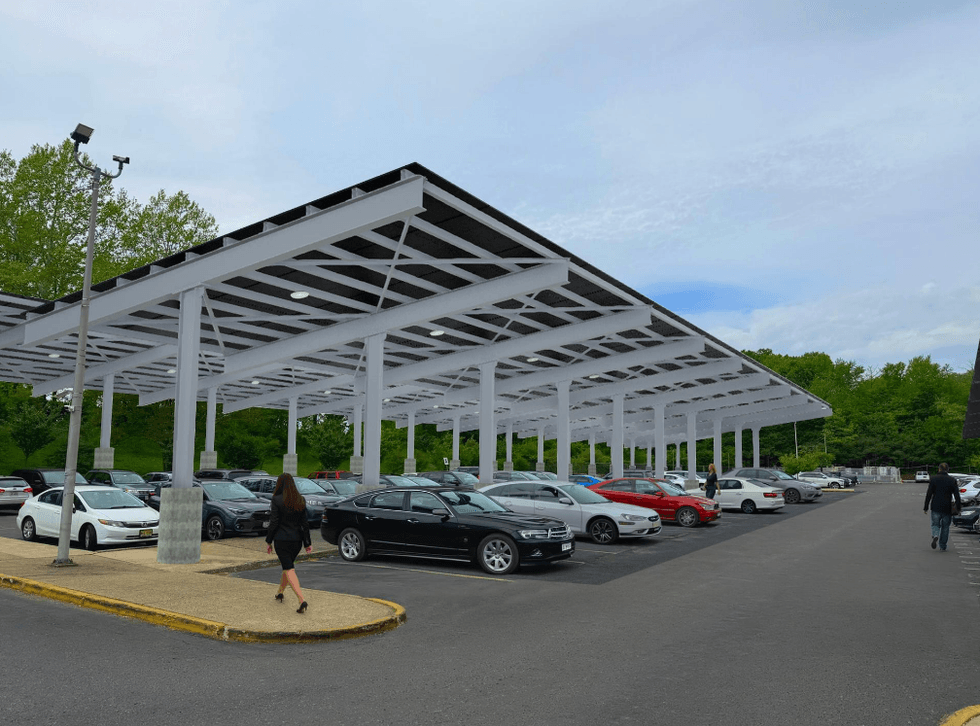 Covered parking lot at the Brooklyn Museum with white canopy and multiple cars, surrounded by trees.
