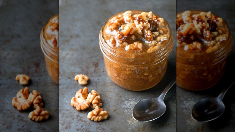 A jar of wet walnuts beside a spoon