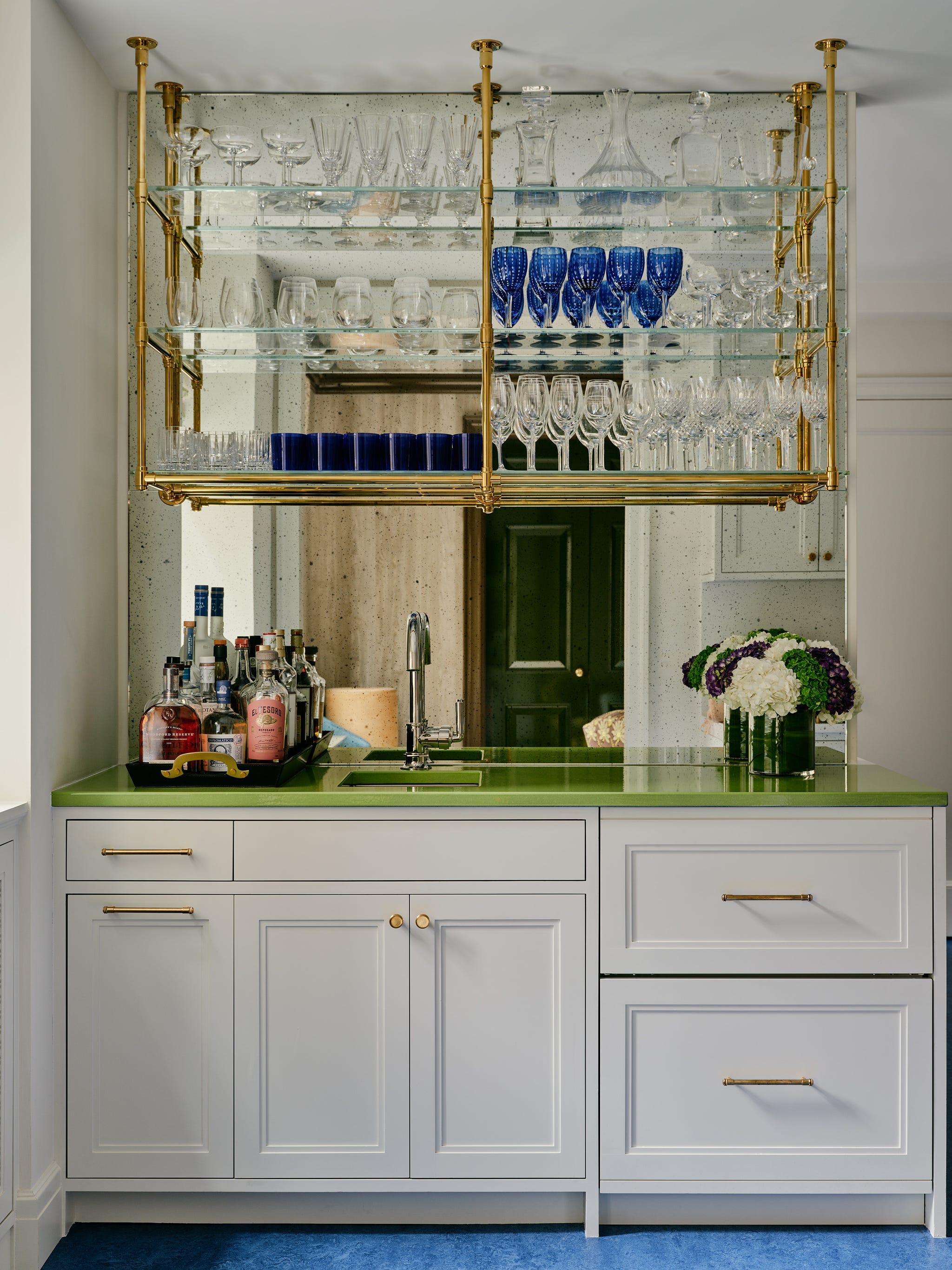 Home bar with mirrored shelves, glassware, and green countertop.