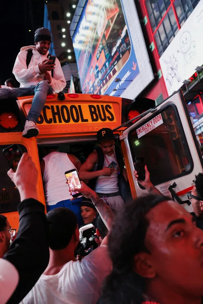 Fans climb inside a school bus parked along 42nd Street in Times Square. REUTERS