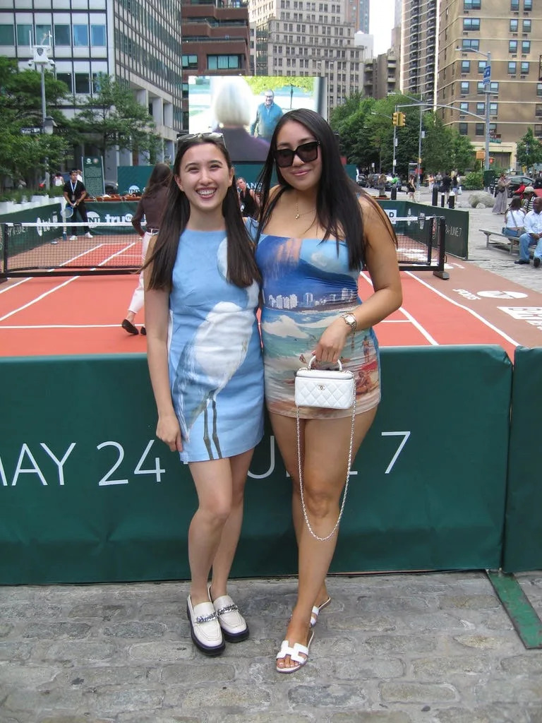Two women in front of a mini tennis court