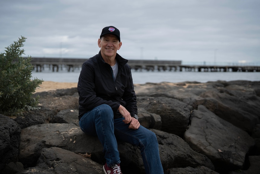 A man sitting on rocks near the ocean.