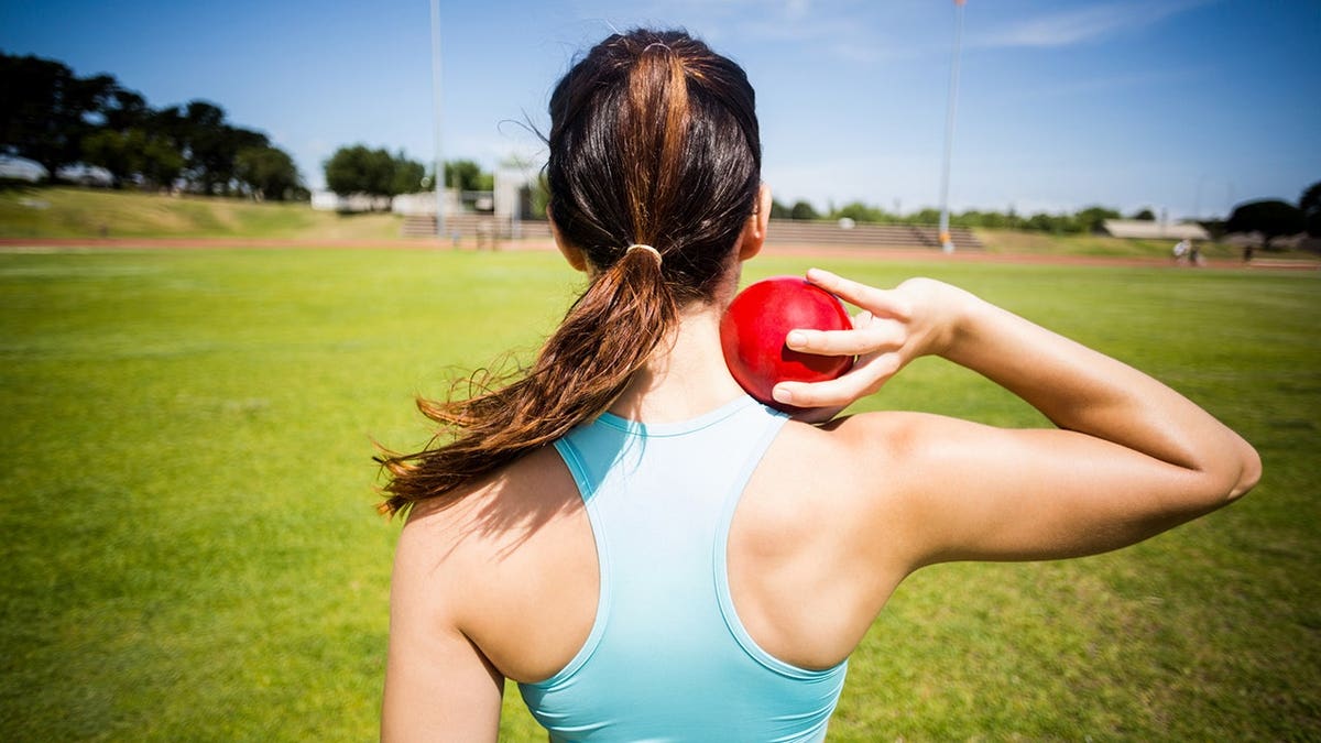 Female athlete preparing to throw shot put ball in stadium
