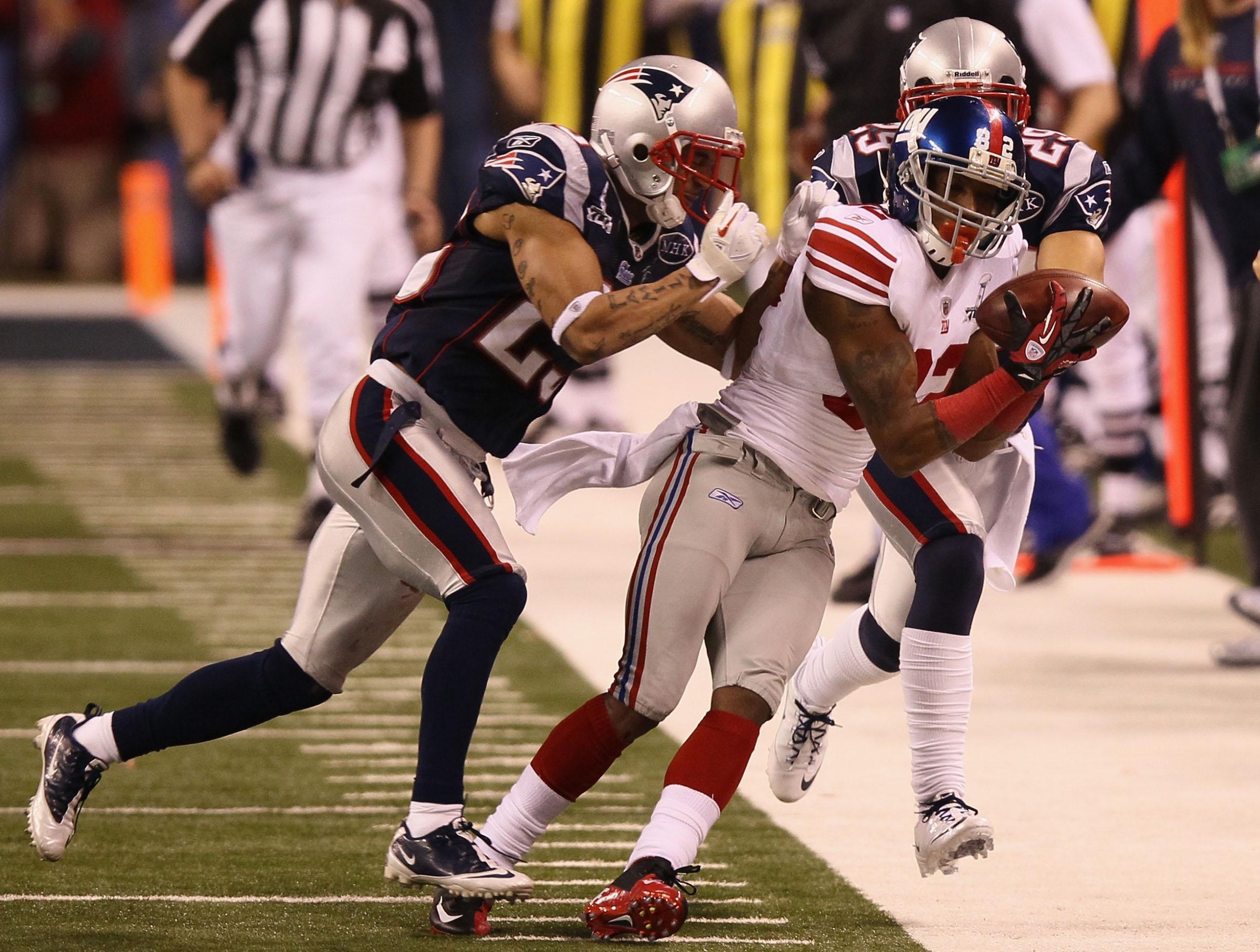 INDIANAPOLIS, IN - FEBRUARY 05: Mario Manningham #82 of the New York Giants makes a catch on the sidelines against Patrick Chung #25 and Sterling Moore #29 of the New England Patriots for a gain of 39 yards in the fourth quarter during Super Bowl XLVI at Lucas Oil Stadium on February 5, 2012 in Indianapolis, Indiana. (Photo by Win McNamee/Getty Images)