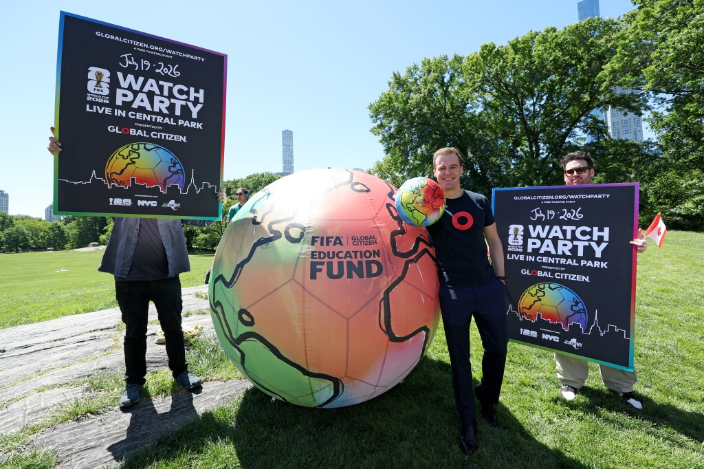 Hugh Evans from Global Citizen poses in Sheep Meadow with two large signs and an inflatable globe to announce the FIFA World Cup 2026 Final Watch Party Live in Central Park.