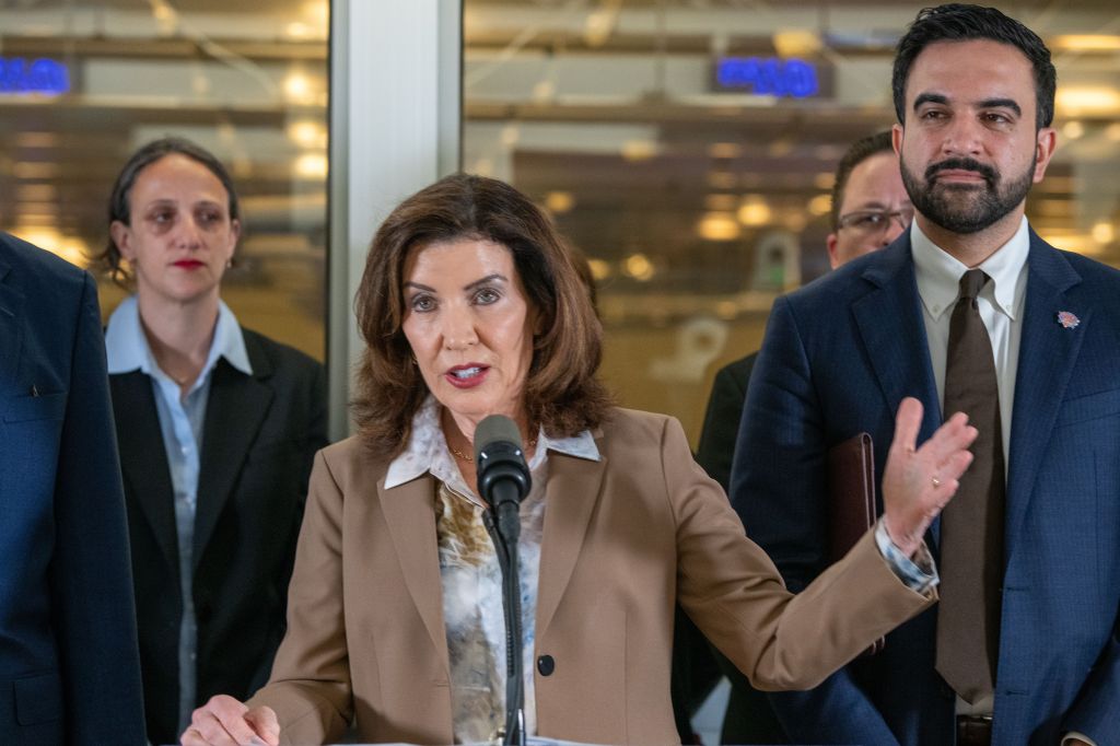 Governor Kathy Hochul speaking at a podium with Mayor Zohran Mamdani standing next to her.