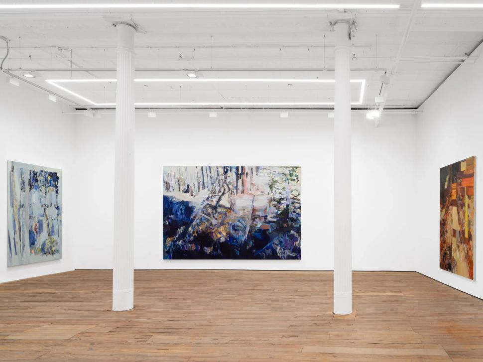 An installation view shows three large abstract paintings arranged across GRIMM New York’s white gallery walls, separated by tall white columns and set against wide wood floorboards.
