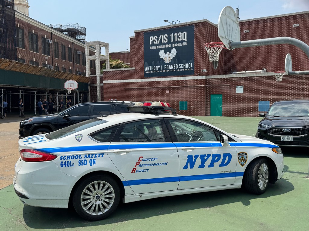 NYPD School Safety vehicle parked on a basketball court in front of PS/IS 113Q where a body was found in a chimney.