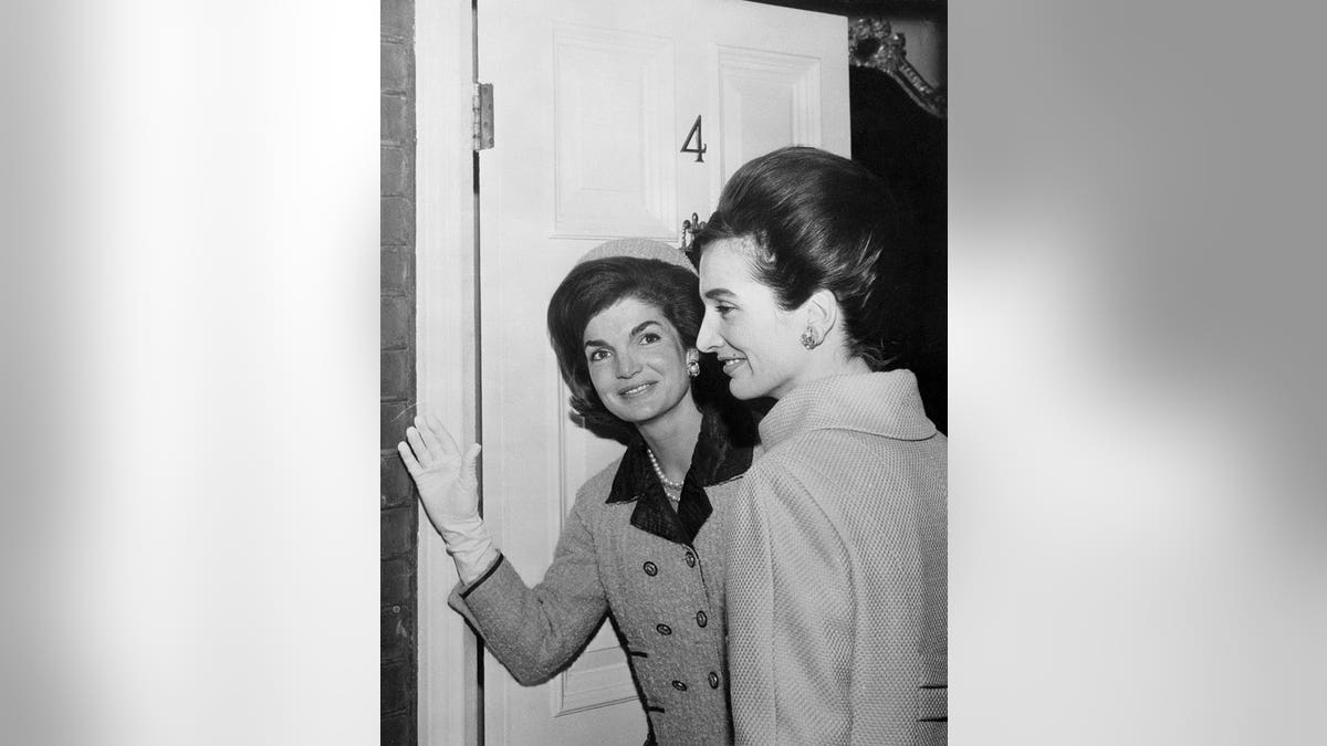 Mrs. Jacqueline Kennedy smiling and waving with Princess Lee Radziwill at a home entrance