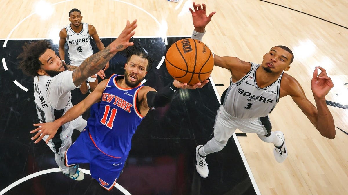 New York Knicks guard Jalen Brunson drives to the basket past San Antonio Spurs forwards Julian Champagnie and Victor Wembanyama