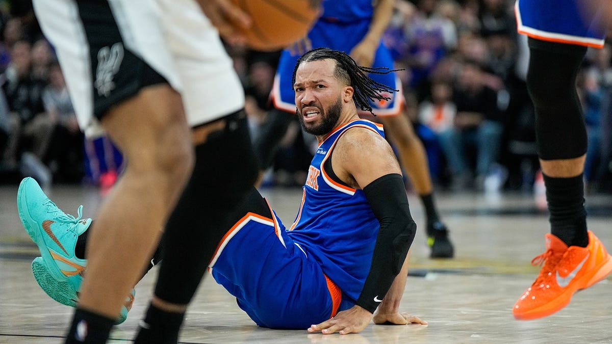 New York Knicks guard Jalen Brunson falling after a foul during a basketball game.