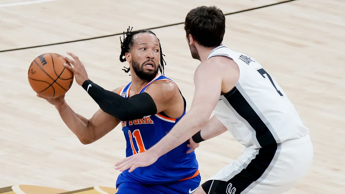 New York Knicks guard Jalen Brunson dribbling basketball against San Antonio Spurs center Luke Kornet in game.