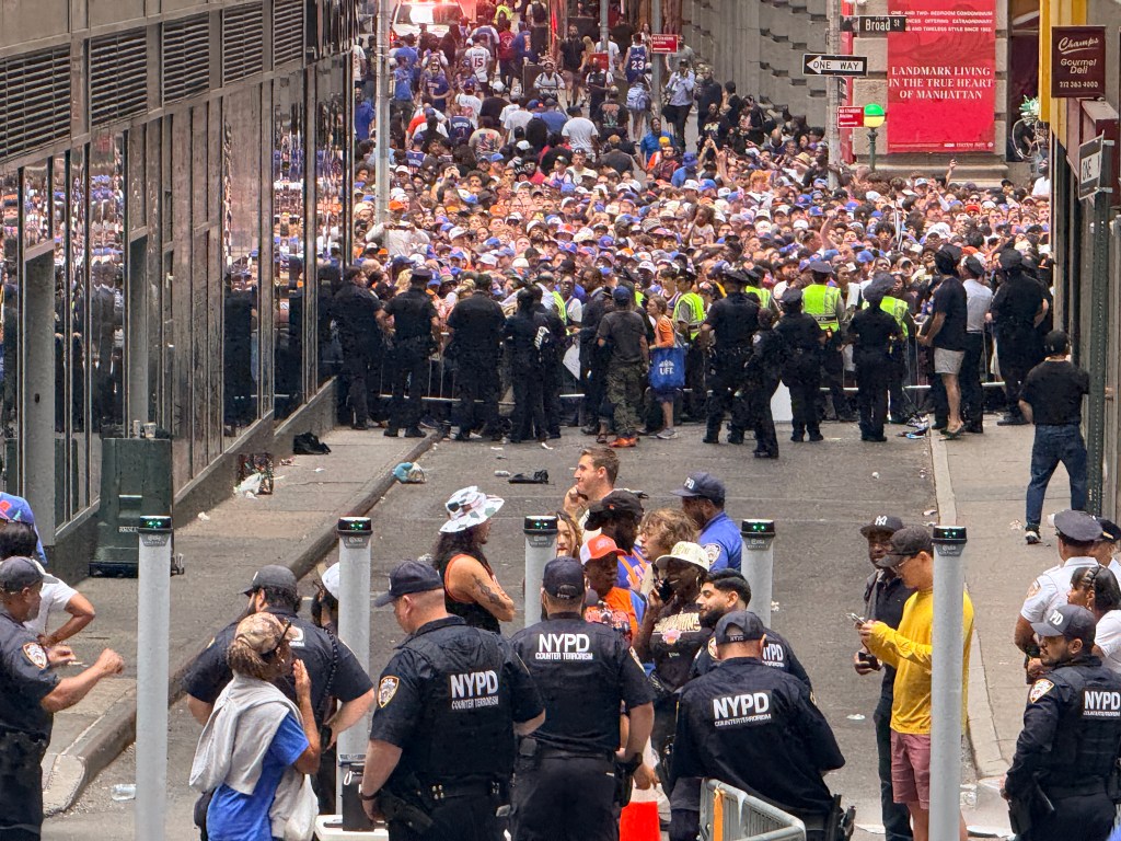 Large crowd of Knicks fans gathered in an intersection with NYPD counter-terrorism officers present.