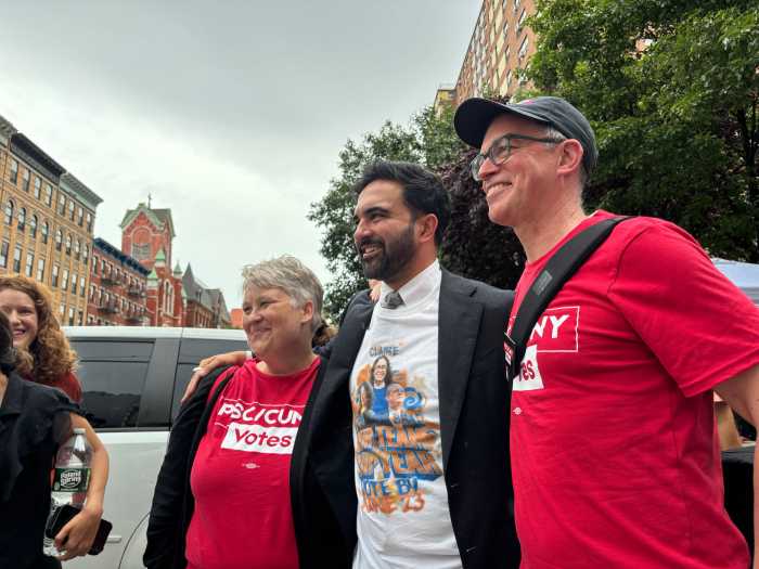 man in a suit standing in between two people wearing red shirts