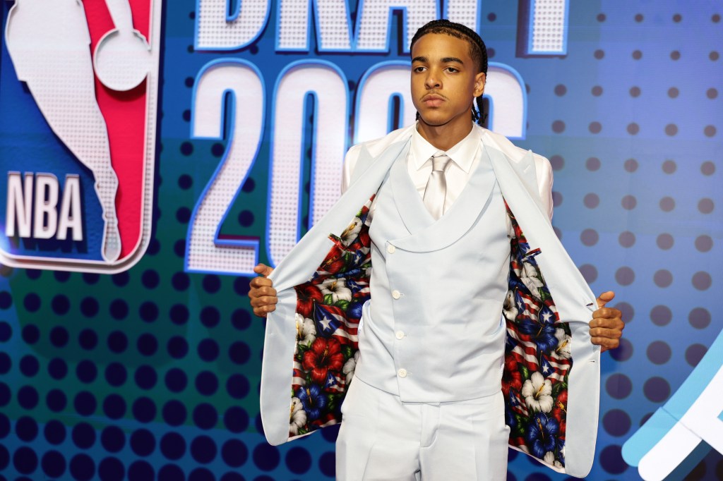 Mikel Brown Jr. in a light blue suit opening his jacket to reveal a lining with hibiscus flowers and the Puerto Rican flag.