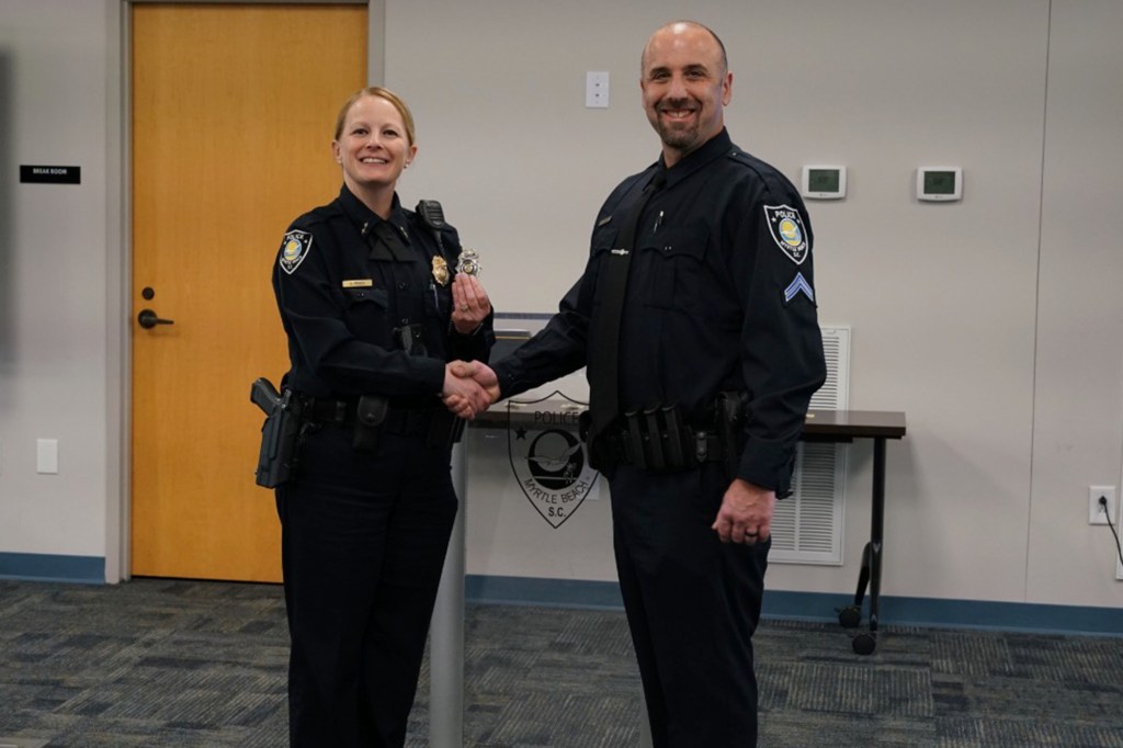 PFC. Michael DeBiase (right) shaking hands with a female police officer as he is promoted to Corporal.