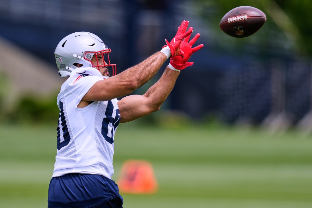 Julian Hill, wearing a white jersey and red gloves, catching a football during practice.