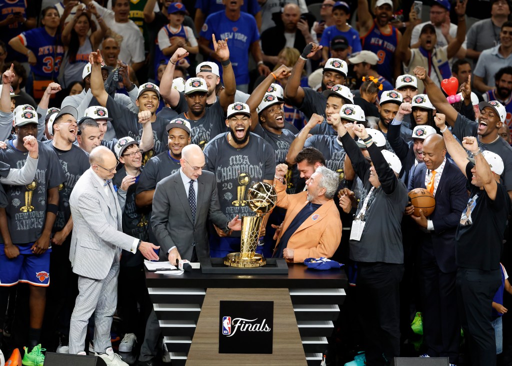 The New York Knicks team and owner James Dolan celebrate with the 2026 NBA Finals trophy.